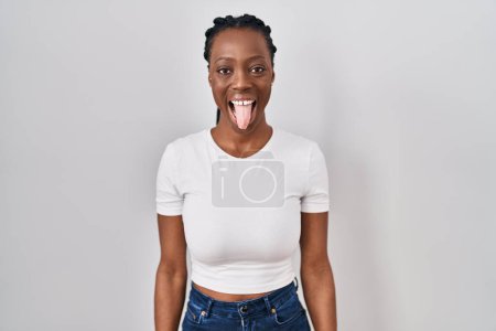 Téléchargez les photos : Belle femme noire debout sur fond isolé langue collante heureux avec une expression drôle. concept d'émotion. - en image libre de droit