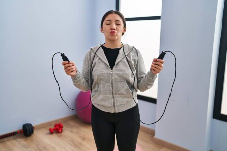 Foto de Young latin woman jumping with skipping rope looking at the camera blowing a kiss being lovely and sexy. love expression. - Imagen libre de derechos