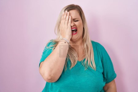 Foto de Caucasian plus size woman standing over pink background yawning tired covering half face, eye and mouth with hand. face hurts in pain. - Imagen libre de derechos