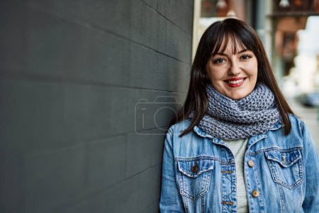 Téléchargez les photos : Jeune femme brune souriante heureuse penchée sur le mur - en image libre de droit