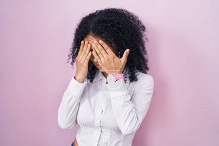 Téléchargez les photos : Hispanic woman with curly hair standing over pink background with sad expression covering face with hands while crying. depression concept. - en image libre de droit