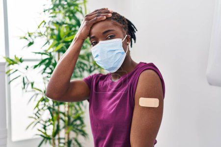 Photo for Beautiful black woman getting vaccine showing arm with band aid stressed and frustrated with hand on head, surprised and angry face - Royalty Free Image