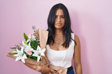Téléchargez les photos : Brunette woman holding bouquet of white flowers skeptic and nervous, frowning upset because of problem. negative person. - en image libre de droit