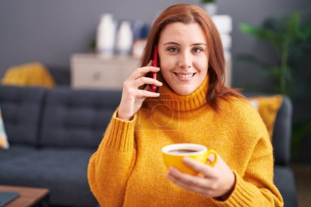Photo for Young beautiful plus size woman talking on smartphone drinking coffee at home - Royalty Free Image