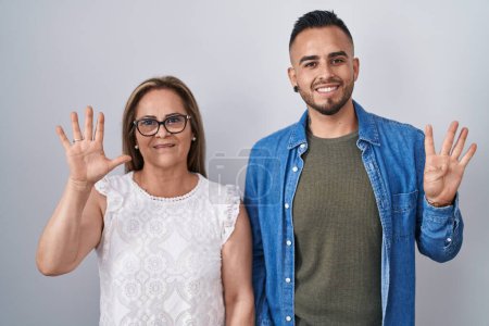 Téléchargez les photos : Hispanic mother and son standing together showing and pointing up with fingers number nine while smiling confident and happy. - en image libre de droit