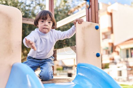 Téléchargez les photos : Enfant trisomique jouant sur la glissière au parc - en image libre de droit