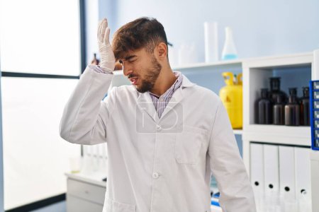 Téléchargez les photos : Arab man with beard working at scientist laboratory surprised with hand on head for mistake, remember error. forgot, bad memory concept. - en image libre de droit
