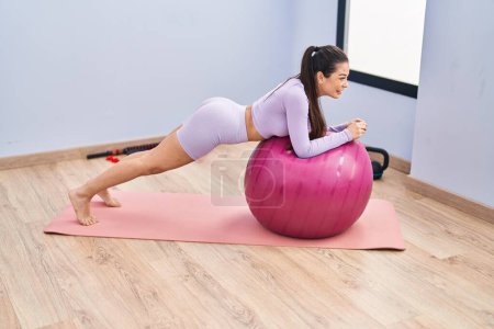 Photo for Young beautiful hispanic woman smiling confident training abs exercise at sport center - Royalty Free Image