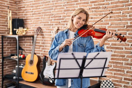 Téléchargez les photos : Jeune femme blonde musicienne jouant du violon au studio de musique - en image libre de droit