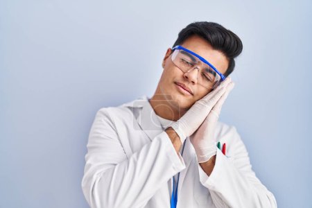 Hispanic man working as scientist sleeping tired dreaming and posing with hands together while smiling with closed eyes. 