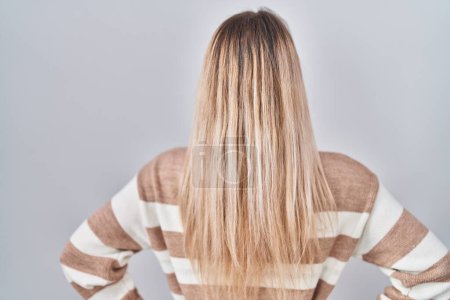 Téléchargez les photos : Jeune femme blonde portant un pull à col roulé sur fond isolé regardant vers l'arrière avec les bras sur le corps - en image libre de droit