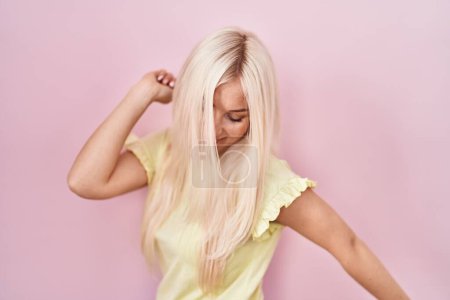 Téléchargez les photos : Caucasian woman standing over pink background dancing happy and cheerful, smiling moving casual and confident listening to music - en image libre de droit