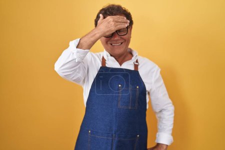 Téléchargez les photos : Middle age hispanic man wearing professional cook apron smiling and laughing with hand on face covering eyes for surprise. blind concept. - en image libre de droit