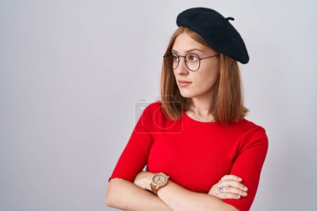 Téléchargez les photos : Young redhead woman standing wearing glasses and beret looking to the side with arms crossed convinced and confident - en image libre de droit