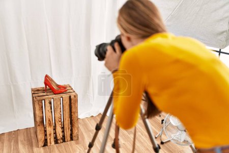 Photo for Young caucasian woman photographer making photo to high heel shoe at photography studio - Royalty Free Image