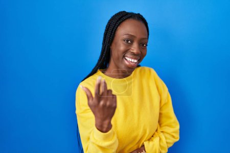 Téléchargez les photos : Belle femme noire debout sur fond bleu appel viennent ici geste avec la main invitant accueillant heureux et souriant - en image libre de droit