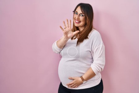 Photo for Pregnant woman standing over pink background showing and pointing up with fingers number five while smiling confident and happy. - Royalty Free Image