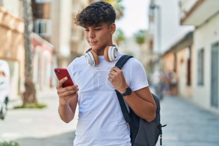 Photo for Young hispanic teenager student smiling confident using smartphone at street - Royalty Free Image