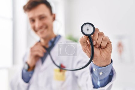Téléchargez les photos : Young man doctor smiling confident holding stethoscope at clinic - en image libre de droit