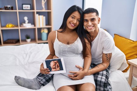 Téléchargez les photos : Jeune couple latin s'attendant bébé se câlinant tenant écographie à la chambre - en image libre de droit