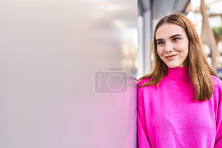 Téléchargez les photos : Jeune femme souriant confiant regardant vers le côté à la rue - en image libre de droit