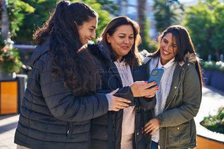 Photo for Three woman mother and daughters using smartphone at park - Royalty Free Image