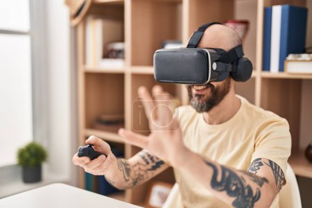 Photo for Young bald man playing video game using virtual reality glasses at home - Royalty Free Image