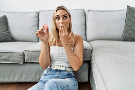Photo for Young blonde woman holding menstrual cup covering mouth with hand, shocked and afraid for mistake. surprised expression - Royalty Free Image
