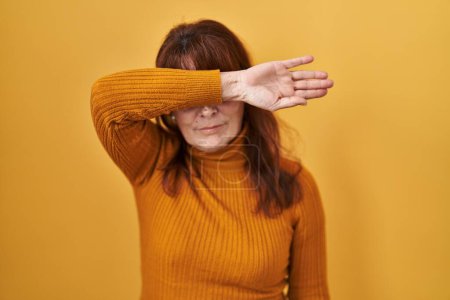 Téléchargez les photos : Middle age hispanic woman standing over yellow background covering eyes with arm, looking serious and sad. sightless, hiding and rejection concept - en image libre de droit