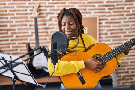 Photo for African american woman musician singing song playing classical guitar at music studio - Royalty Free Image