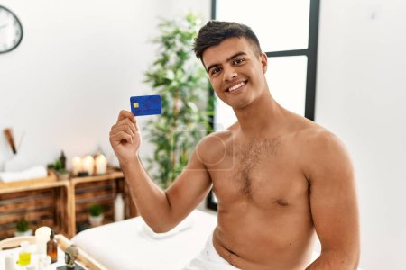 Téléchargez les photos : Young hispanic man smiling confident holding credit card at beauty center - en image libre de droit