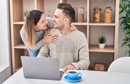 Foto de Hombre y mujer pareja abrazándose el uno al otro usando el ordenador portátil en casa - Imagen libre de derechos