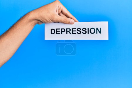 Photo for Hand of caucasian man holding paper with depression word over isolated blue background - Royalty Free Image