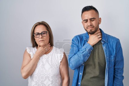 Téléchargez les photos : Mère hispanique et son fils debout ensemble toucher le cou douloureux, mal de gorge pour la grippe, la motte et l'infection - en image libre de droit
