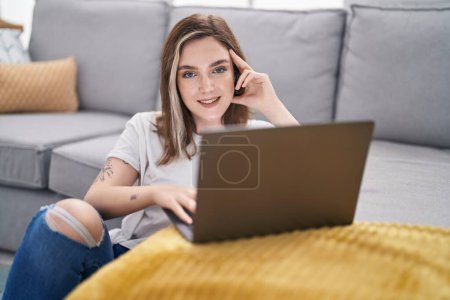 Photo for Young woman using laptop sitting on floor at home - Royalty Free Image