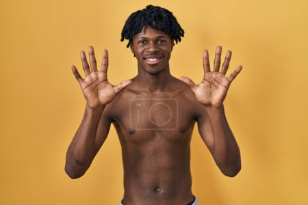 Photo for Young african man with dreadlocks standing shirtless showing and pointing up with fingers number ten while smiling confident and happy. - Royalty Free Image