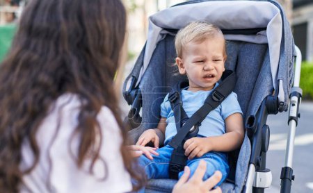 Photo for Mother and son sitting on stroller baby crying at street - Royalty Free Image