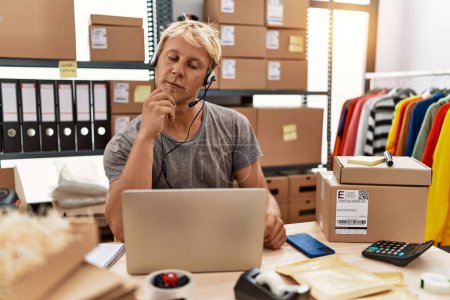Photo for Young blond man wearing operator headset working at online shop serious face thinking about question with hand on chin, thoughtful about confusing idea - Royalty Free Image