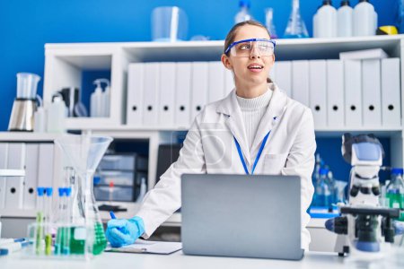 Photo for Young woman scientist smiling confident using laptop at laboratory - Royalty Free Image
