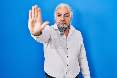 Photo for Middle age man with grey hair standing over blue background doing stop sing with palm of the hand. warning expression with negative and serious gesture on the face. - Royalty Free Image