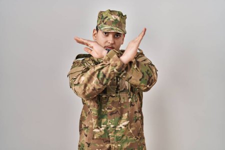 Foto de Hombre árabe joven usando camuflaje ejército uniforme rechazo expresión cruzando brazos haciendo signo negativo, cara enojada - Imagen libre de derechos