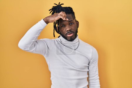 Photo for African man with dreadlocks wearing turtleneck sweater over yellow background pointing unhappy to pimple on forehead, ugly infection of blackhead. acne and skin problem - Royalty Free Image