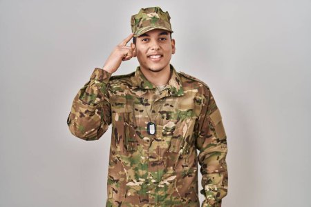 Foto de Young arab man wearing camouflage army uniform smiling pointing to head with one finger, great idea or thought, good memory - Imagen libre de derechos