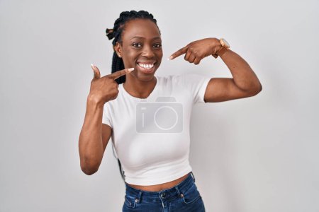 Foto de Beautiful black woman standing over isolated background smiling cheerful showing and pointing with fingers teeth and mouth. dental health concept. - Imagen libre de derechos