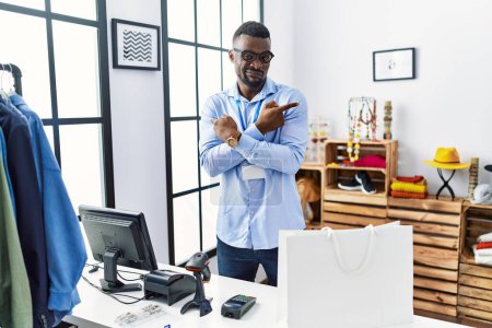 Foto de Young african man working as manager at retail boutique pointing to both sides with fingers, different direction disagree - Imagen libre de derechos