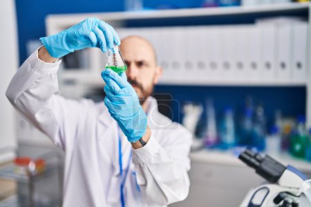 Téléchargez les photos : Jeune homme chauve scientifique tenant une éprouvette en laboratoire - en image libre de droit