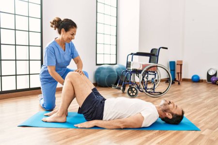 Photo for Middle age man and woman smiling confident having rehab session stretching at physiotherapy clinic - Royalty Free Image