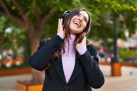 Téléchargez les photos : Young hispanic woman listening to music and dancing at park - en image libre de droit