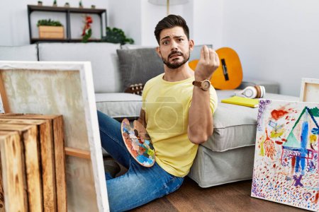 Téléchargez les photos : Young man with beard painting canvas at home doing italian gesture with hand and fingers confident expression - en image libre de droit