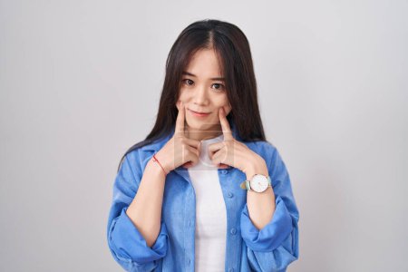 Téléchargez les photos : Jeune femme chinoise debout sur fond blanc souriant avec la bouche ouverte, les doigts pointant et forçant sourire joyeux - en image libre de droit